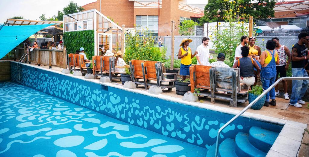 Guests gathered around a converted pool patio with a painted turquoise wave mural