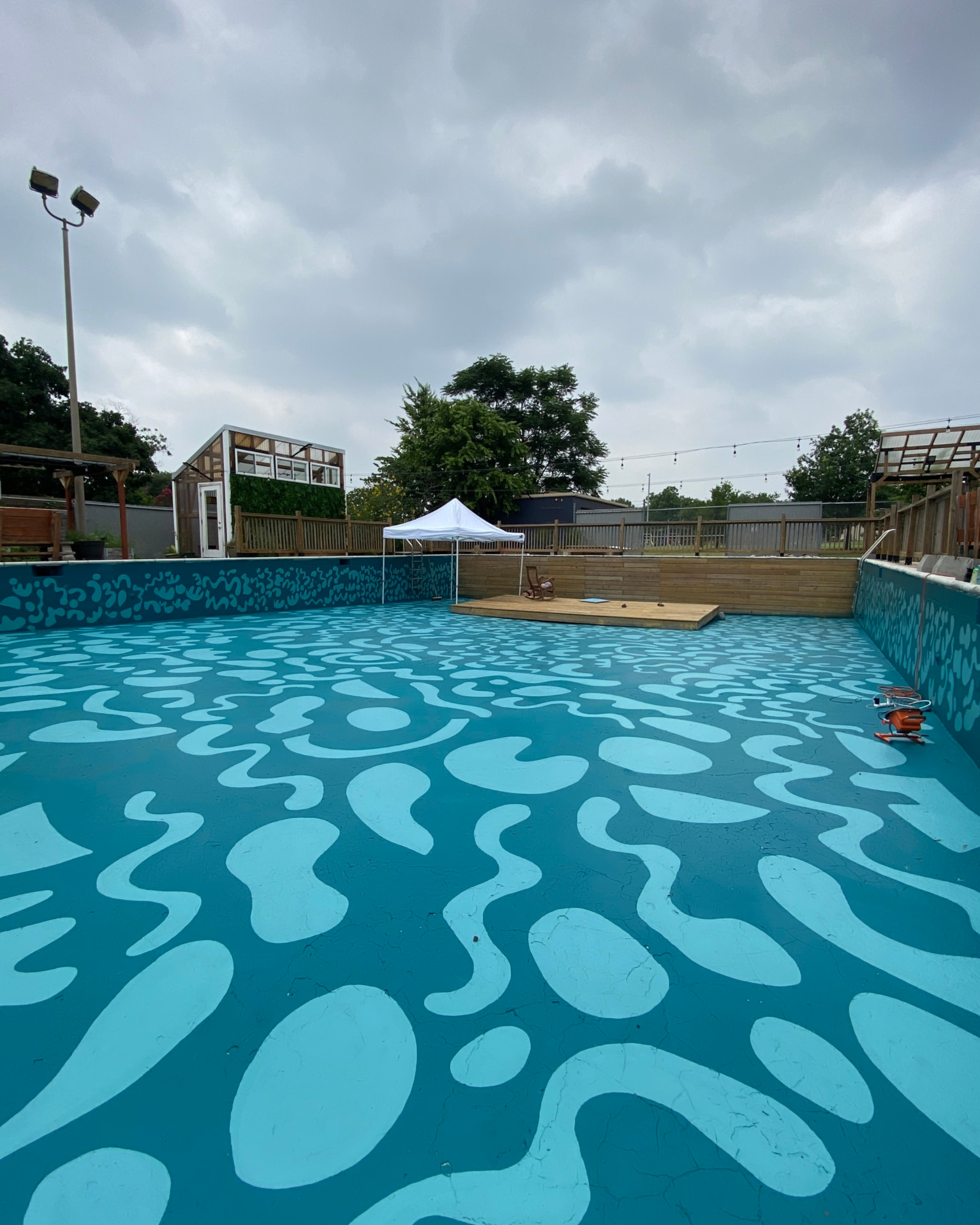 Empty swimming pool painted with a flowing turquoise wave pattern across floor and walls